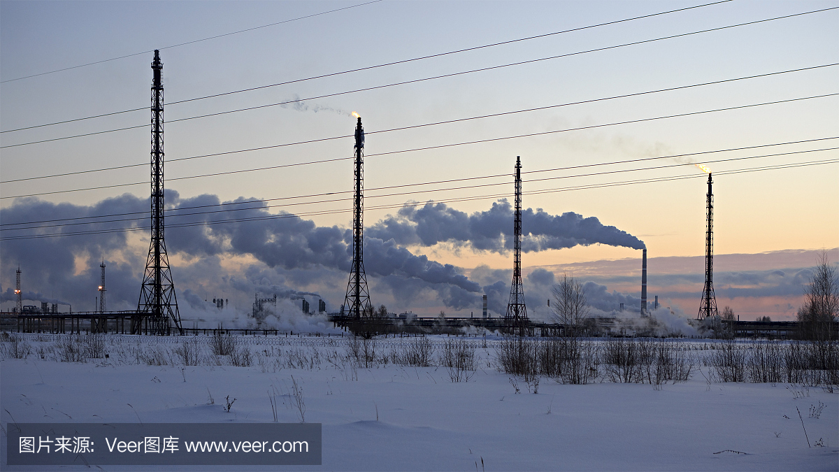 炼油厂在日落天空的背景。寒冷多雪的冬夜